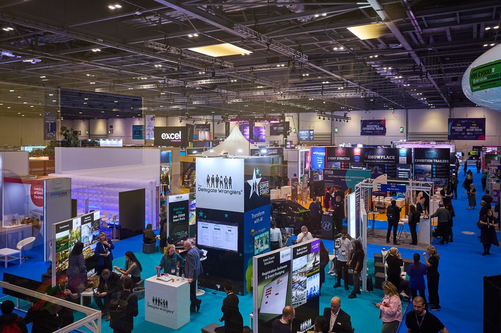 Multiple exhibition stands at Confex, including displays with bright fairy lights and busy crowds of attendees networking and exploring.
